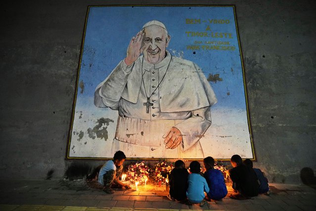 Children light candles near a mural of Pope Francis in Dili, East Timor, Friday, April 25, 2025. (Photo by Firdia Lisnawati/AP Photo)