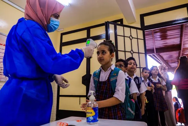 A staff member of the Rosary Sisters school in Gaza City checks the temperature of returning students on the first day of school, after local authorities eased some of the restrictions that were imposed in a bid to slow the spread of the novel coronavirus, on August 8, 2020. (Photo by Mahmud Hams/AFP Photo)