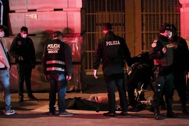 Police officers check a body of a victim outside a disco in Lima, Peru, Sunday, August 23, 2020. Officials said over a dozen people died in a stampede at the disco after a police raid to enforce the country's lockdown during the coronavirus pandemic. (Photo by Diego Vertiz/AP Photo)