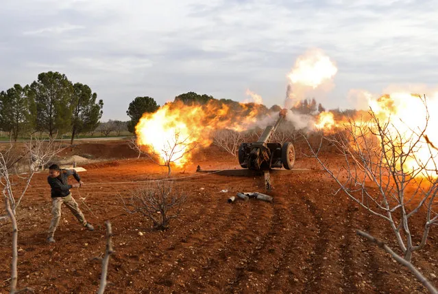 An opposition fighter fires a gun from a village near al-Tamanah during ongoing battles with government forces in Syria's Idlib province on January 11, 2018. The regime hopes to seize control of southeast parts of Idlib province to secure a main road between the capital Damascus and the northern city of Aleppo. (Photo by Omar Haj Kadour/AFP Photo)