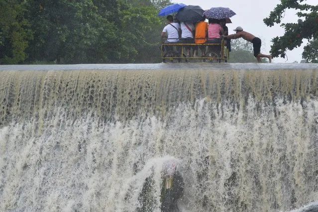 Residents cross a swelling dam, due to rising waters brought about by Typhoon Koppu, in Las Pinas city, metro Manila October 19, 2015. (Photo by Ezra Acayan/Reuters)