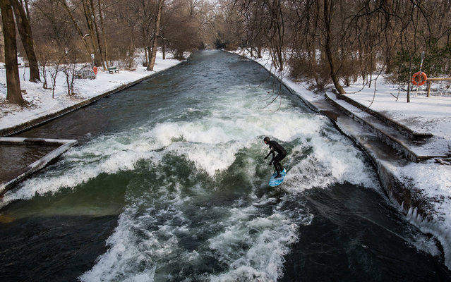 A surfer rides on a wave of the Eisbach creek in the English Garden park in Munich, Germany, Bavaria, Germany, 27 February 2018. Media reports state that extreme cold weather is forecast to hit many parts of Europe with temperatures plummeting to a possible ten year low. (Photo by Lukas Barth/EPA/EFE)
