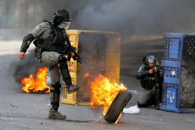 An Israeli border police officer kicks a burning tire as Palestinians take part in an anti-Israel protest in Hebron in the Israeli-occupied West Bank on October 23, 2020. (Photo by Mussa Qawasma/Reuters)