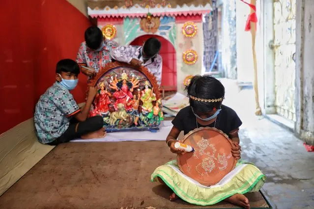 Children from Sundarban, wearing protective masks, give finishing touches to the artwork and paintings of goddess Durga prior to the Durga puja festival amidst Covid-19 pandemic in Kolkata, West Bengal, India on October 18, 2020. (Photo by Jit Chattopadhyay/SOPA Images/LightRocket via Getty Images)