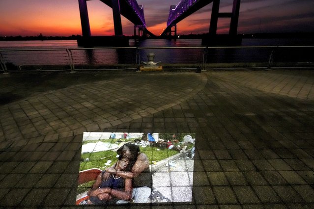 This photo showing flood victims sitting at the Ernest N. Morial Convention Center where they had been waiting for days to be evacuated in the aftermath of Hurricane Katrina in New Orleans, taken by AP photographer Eric Gay, is projected Tuesday, August 26, 2025, along the Mississippi River behind the convention center. (Photo by Gerald Herbert/AP Photo)