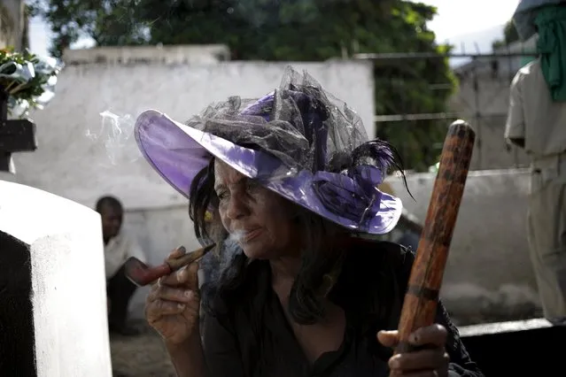A woman smokes during Day of the Dead celebrations at the National Cemetery in Port-au-Prince, Haiti, November 1, 2015. (Photo by Andres Martinez Casares/Reuters)