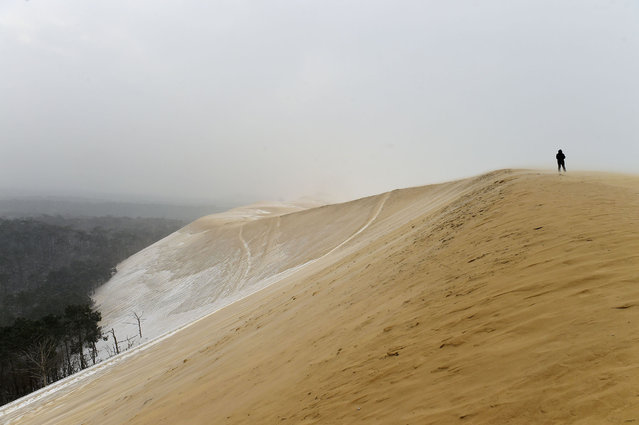 A man walks on the partially snow covered Pyla sand dune after snow fall on February 28, 2018 in La Teste-de-Buch, southwestern France. Europe remained on February 28 gripped by a blast of Siberian weather, accounting for at least 24 deaths and carpeting palm-lined Mediterranean beaches in snow. (Photo by Nicolas Tucat/AFP Photo)