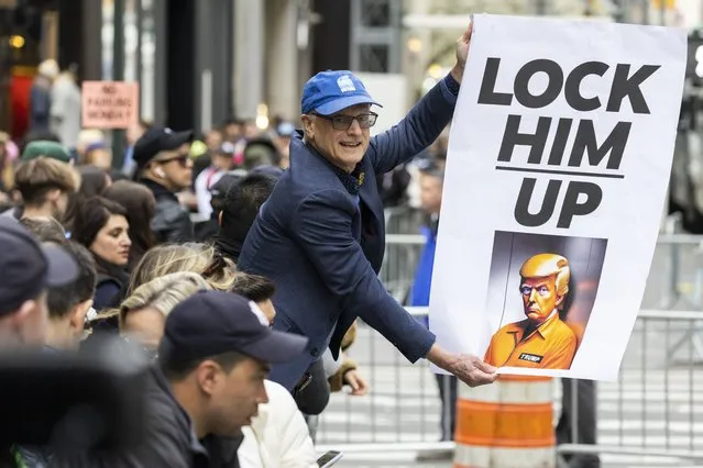 A protester holds a placard outside Trump Tower in New York on Monday, April 3, 2023. Former President Donald Trump is expected to be booked and arraigned on Tuesday on charges arising from hush money payments during his 2016 campaign. (Photo by Corey Sipkin/AP Photo)