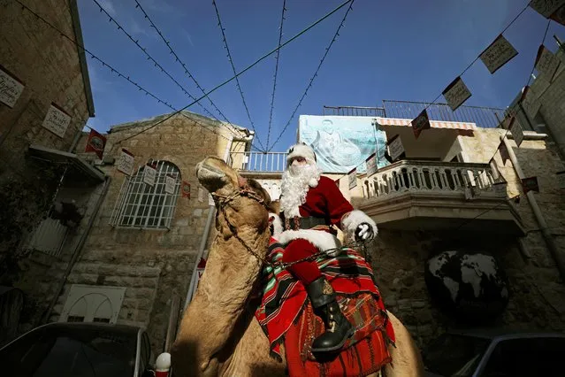 Issa Kassissieh wears a Santa Claus costume as he rides a camel after handing out Christmas trees to people during the annual distribution of the trees organized by the Jerusalem municipality in Jerusalem's Old City on December 22, 2020. (Photo by Ammar Awad/Reuters)