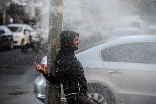 A protester reacts as Turkish anti-riot police use water cannon, on October 26, 2016 during a demonstration against the detention of the Kurdish-majority city's co-mayors in Diyarbakir. Gultan Kisanak and Firat Anli were taken into custody on October 25, 2016 at night in a surprise move against the leaders of a city hit by renewed fighting between Turkish forces and members of the outlawed Kurdistan Workers' Party (PKK). At least 25 protesters were now in custody, security sources told AFP. (Photo by Ilyas Akengin/AFP Photo)