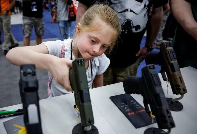 Rachel, 7, holds a handgun at the National Rifle Association (NRA) annual convention in Indianapolis, Indiana, U.S., April 15, 2023. (Photo by Evelyn Hockstein/Reuters)
