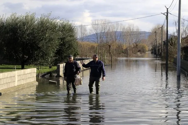 Local residents walk on a flooded road after heavy rainfalls in Obot village, about 100 kilometres (60 miles) northwest of Tirana, Albania, Monday, January 11, 2021. Heavy rainfall and snow during the last days has flooded many areas in the country, authorities said on Monday. Thousands of hectares (acres) have been flooded in western Albania where authorities have evacuated scores of them. (Photo by Hektor Pustina/AP Photo)