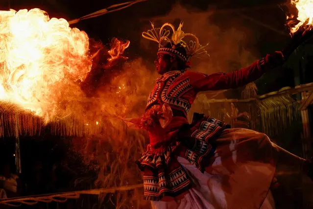 A Sri Lankan dancer performs with fire at a Gammaduwa performance, a traditional low country healing ritualistic performance, at a Buddhist temple, in Colombo, Sri Lanka on March 31, 2023. (Photo by Dinuka Liyanawatte/Reuters)