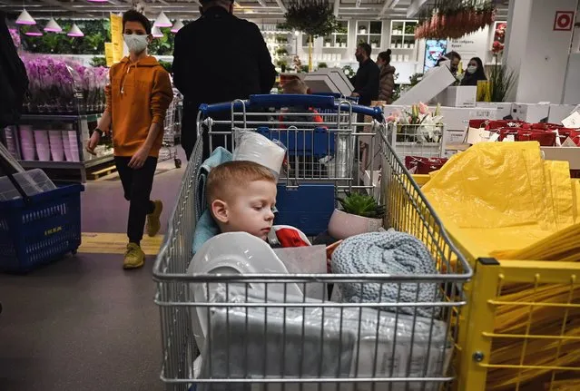 A child sits in a shopping trolley while his parents shop in a store in Moscow on December 28, 2020, amid the crisis linked with the Covid-19 pandemic caused by the novel coronavirus. Russia confirmed 27,787 new daily Covid-19 cases including 6,253 in Moscow. (Photo by Alexander Nemenov/AFP)