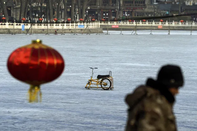 A worker walks by a specially made steel sled parked alone on the capital popular ice skating frozen Houhai Lake after it was ordered to close following the coronavirus cases surge, in Beijing, Thursday, January 21, 2021. China is making some of its toughest travel restrictions yet as coronavirus cases surge in several northern provinces ahead of the travel rush for Lunar New Year next month. (Photo by Andy Wong/AP Photo)