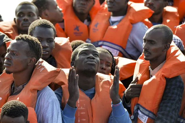 Migrants and refugees seated on a rubber boat wait to be rescued by the Topaz Responder, a rescue ship run by Maltese NGO “Moas” and the Italian Red Cross, on November 4, 2016 off the Libyan coast. Around 750 migrants were rescued across the Mediterranean on November 3, 2016 by the Italian coast guard, a Frontex ship, a Save The Children vessel, German NGO Jugend Rettet's Iuventa and two boats run by the Malta-based MOAS (Migrant Offshore Aid Station). But at least 110 migrants are feared drowned after they were forced at gunpoint to set sail from Libya, while many more may have died in a separate shipwreck, survivors said. (Photo by Andreas Solaro/AFP Photo)