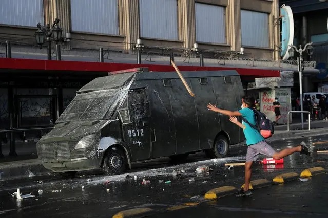 A demonstrator throws a wood stick toward a riot police vehicle during a protest against Chile's President Sebastian Pinera and his government, during Pinera's birthday, in Santiago, Chile on December 1, 2020. (Photo by Ivan Alvarado/Reuters)