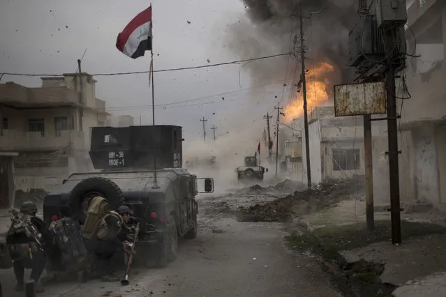 A car bomb explodes next to Iraqi special forces armored vehicles as they advance towards Islamic State held territory in Mosul, Iraq, Wednesday, November 16, 2016. Troops have established a foothold in the city's east from where they are driving northward into the Tahrir neighborhood. The families in Tahrir are leaving their homes to flee the fighting. (Photo by Felipe Dana/AP Photo)