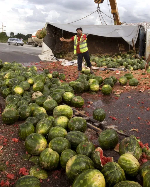 A man clears a road after a truck overturned, spilling watermelons, on the way to market in Thuman, Albania June 26, 2009. (Photo by Adam Tanner/Reuters)