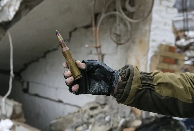 A member of the armed forces of the separatist self-proclaimed Donetsk People's Republic holds up a large-caliber bullet for the camera in Vuhlehirsk, Donetsk region, February 4, 2015. (Photo by Maxim Shemetov/Reuters)