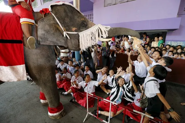 Children receive a puppet from an elephant as they attend a Christmas festival in a primary school in Ayutthaya, Thailand, December 24, 2015. (Photo by Jorge Silva/Reuters)