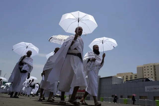 Muslim pilgrims walk, holding their umbrellas at the Mina tent camp, in Mecca, Saudi Arabia, during the annual hajj pilgrimage, Monday, June 26, 2023. Muslim pilgrims are converging on Saudi Arabia's holy city of Mecca for the largest hajj since the coronavirus pandemic severely curtailed access to one of Islam's five pillars. (Photo by Amr Nabil/AP Photo)