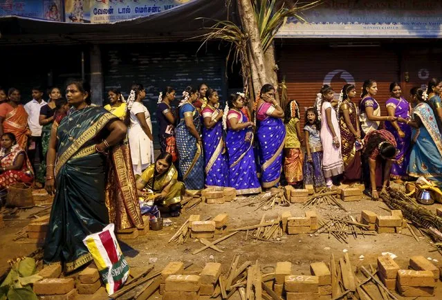 Devotees stand in line to collect utensils and ingredients for preparing ritual rice dishes to offer to the Hindu Sun God as they attend Pongal celebrations at a slum in Mumbai, India, January 15, 2016. (Photo by Danish Siddiqui/Reuters)