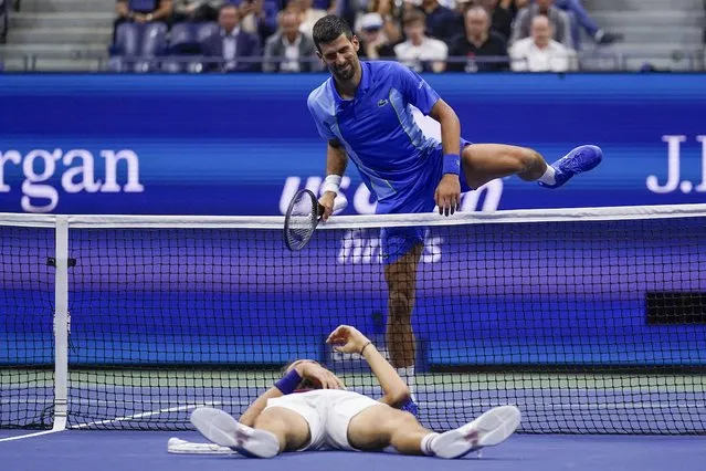 Novak Djokovic, of Serbia, climbs over the net to check on Daniil Medvedev, of Russia, who laid on the court after a rally during the men's singles final of the U.S. Open tennis championships, Sunday, September 10, 2023, in New York. (Photo by Charles Krupa/AP Photo)