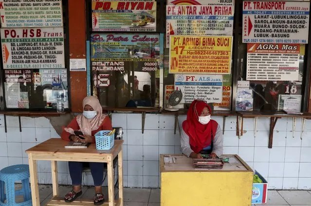 Employees wait for customers at the ticket counters at the Kalideres bus terminal in Jakarta, Indonesia, Wednesday, May 5, 2021. The mass exodus out of major cities in the world's most populous Muslim country is underway despite travel restrictions imposed by the government to prevent the spread of coronavirus outbreak, as people are heading home to their villages to celebrate Eid al-Fitr holiday that marks the end of the holy fasting month of Ramadan on May 13. (Photo by Tatan Syuflana/AP Photo)