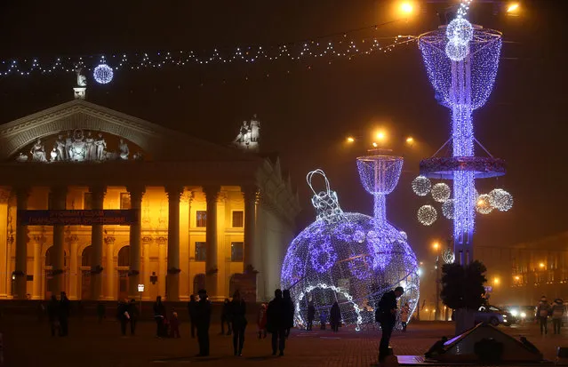 People are seen near a giant illuminated Christmas ball installed on Oktyabrskaya Square for the upcoming New Year and Christmas season in Minsk, Belarus December 21, 2016. (Photo by Vasily Fedosenko/Reuters)