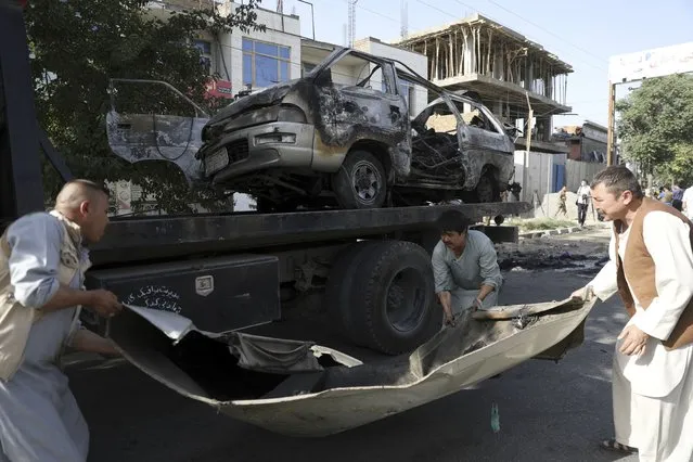 Security personnel remove a damaged minivan after a bomb explosion in Kabul, Afghanistan, Saturday, June 12, 2021. Separate bombs hit two minivans in a mostly Shiite neighborhood in the Afghan capital Saturday, killing several people and wounding others, the Interior Ministry said. (Photo by Rahmat Gul/AP Photo)