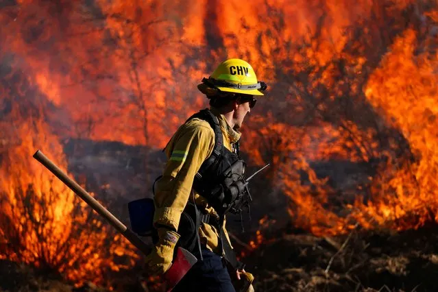 A firefighter works to extinguish the Highland Fire, a wind driven wildfire near Aguanga, California, U.S., October 31, 2023. (Photo by Mike Blake/Reuters)