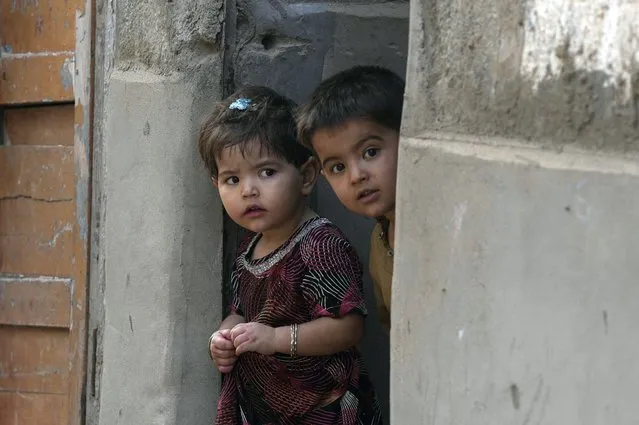 Afghan refugee children look to Pakistani police officers conducts biometric identification of a residents during a search operation against illegal immigrants at a neighbourhood of Karachi, Pakistan, Tuesday, November 21, 2023. (Photo by Fareed Khan/AP Photo)