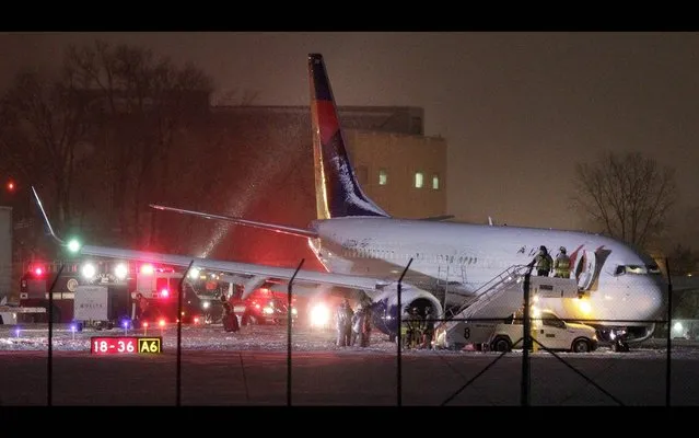 Authorities investigate the scene of a Delta Air Lines Boeing 737-800 jet that slid off a runway in the snow after arriving at Dane County Regional Airport in Madison, Wis., Monday, December 16, 2013. No one was hurt. (Photo by M. P. King/AP Photo/Wisconsin State Journal)