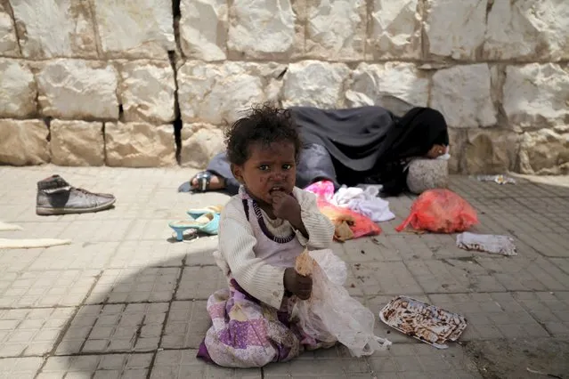 A girl sits in front of  her mothr sleeping on the sidewalk in a street in Sanaa April 11, 2015. The humanitarian situation is witnessing a marked deterioration, a result of the war waged by the Saudi-led coalition forces According to media. (Photo by Mohamed al-Sayaghi/Reuters)