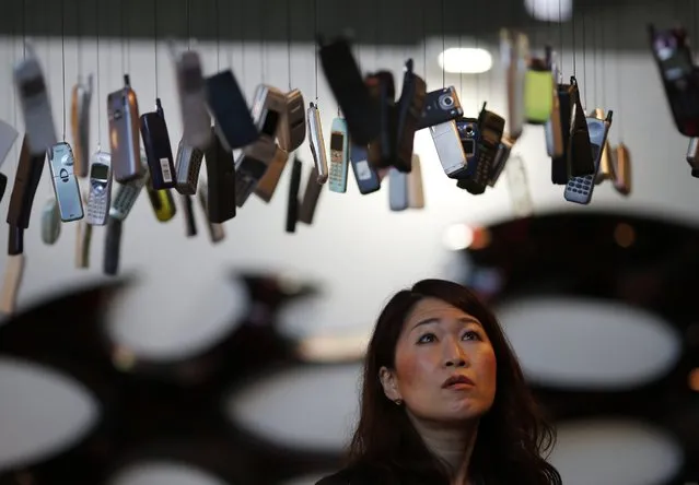 A visitor looks up an art installation of mobile phones hanging from the ceiling displayed by collector Yuichi Kogure at the “Room 32” fashion and design exhibition in Tokyo, Friday, February 19, 2016. (Photo by Shuji Kajiyama/AP Photo)