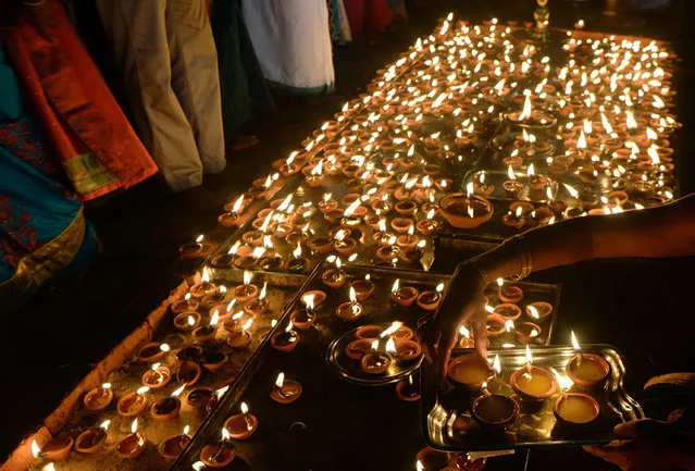 A Sri Lankan Hindu devotee offers prayers while holding oil lamps during the Maha Shivaratri festival at a Hindu temple in Colombo on March 4, 2019. The festival of Maha Shivaratri is marked by Hindus fasting and offering prayers in a night long vigil. (Photo by Lakruwan Wanniarachchi/AFP Photo)