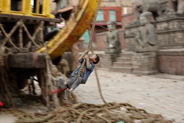 A boy hangs from a rope in front of a historic temple at Vhaktapur district in Nepal 27 April 2015. The death toll from this weekend's earthquake in Nepal is now at 4,138, reports the country's Interior Ministry. (Photo by Abir Abdullah/EPA)