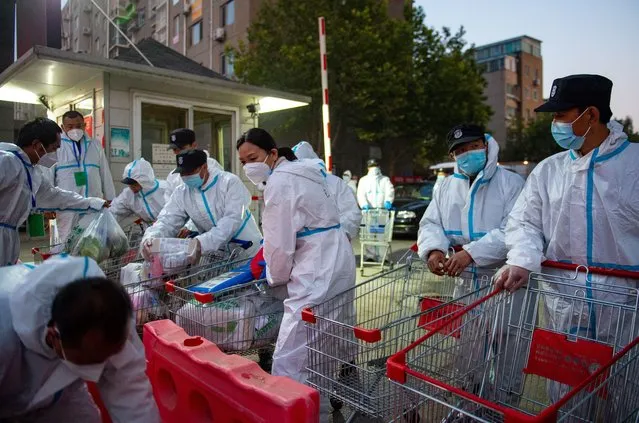 Epidemic prevention and control staff members arrange daily necessities for residents at the Hongfuyuan residential community in Changping District of Beijing, capital of China, October 23, 2021. The Hongfuyuan residential community was listed as high risk of COVID-19 on Saturday and has been put under closed-off management. (Photo by Xinhua News Agency/Rex Features/Shutterstock)