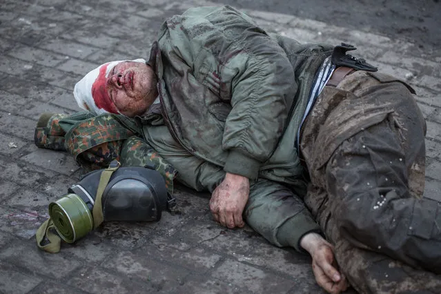 An injured anti-government protester lies on the ground during clashes with riot police outside Ukraine's parliament on February 18, 2014 in Kiev, Ukraine. (Photo by Vladislav Sodel/Kommersant Photo via Getty Images)