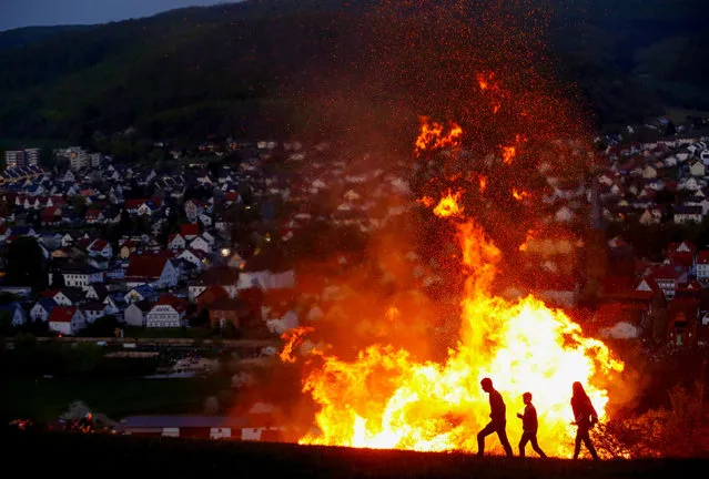 People walk in front of an Easter fire during the celebration of the traditional “Osterraederlauf” in Luegde, Germany, April 21, 2019. (Photo by Thilo Schmuelgen/Reuters)
