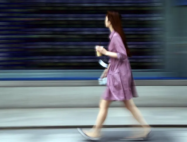 A woman walks by an electronic stock board of a securities firm in Tokyo, Friday, May 15, 2015. Shares in Asia were uneven on Friday as the big markets in Japan and Hong Kong got a lift from the rebound on Wall Street, but weak data dragged Chinese shares lower. (Photo by Koji Sasahara/AP Photo)