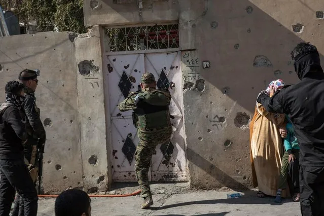 In this Tuesday February 21, 2017 photo, Iraqi security forces enter a house while searching for suspected Islamic State group fighters, in Mosul, Iraq. The security forces launch three or four raids a week, arresting suspected IS members still living in the city. (Photo by John Beck/AP Photo)