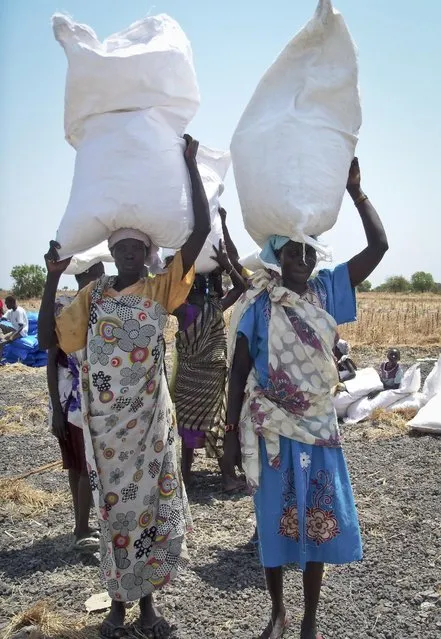 In this photo taken Wednesday, March 1, 2017, women carry away food aid distributed by the World Food Program (WFP) back to their families, in Padeah, South Sudan. South Sudanese who fled famine and fighting in Leer county emerged from South Sudan's swamps after months in hiding to receive food aid being distributed by the World Food Program. (Photo by Sam Mednick/AP Photo)