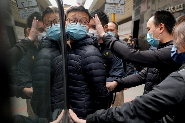 Editor of Stand News Patrick Lam, center, is escorted by police officers into a van after they searched evidence at his office in Hong Kong, Wednesday, December 29, 2021. Hong Kong police raided the office of the online news outlet on Wednesday after arresting several people for conspiracy to publish a seditious publication. (Photo by Vincent Yu/AP Photo)