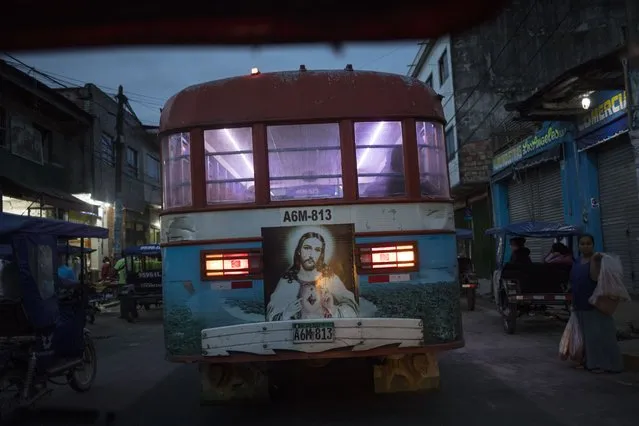 A Sacred Heart of Jesus Christ image decorates the back of a public bus in Iquitos, Peru, early Saturday, March 20, 2021. Almost a year ago, dozens of victims were clandestinely buried in Iquitos, a city in Loreto state in the heart of the Peruvian Amazon. Local authorities approved the burials but never told the families, who believed their loved ones were in a local cemetery – and only a couple of months later they found out the truth. (Photo by Rodrigo Abd/AP Photo)