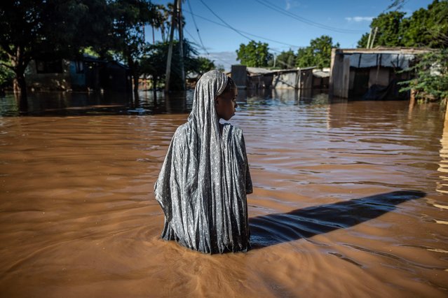 A woman wades through flood waters at an inundated residential area in Garissa, on May 9, 2024. Kenya is grappling with one of its worst floods in recent history, the latest in a string of weather catastrophes, following weeks of extreme rainfall scientists have linked to a changing climate. At least 257 people have been killed and more than 55,000 households have been displaced as murky waters submerge entire villages, destroy roads and inundate dams. (Photo by Luis Tato/AFP Photo)
