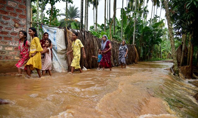 Villagers wade through a flooded road following heavy rains after cyclone Remal's landfall at Singi Mari village of Nagaon district, in India's Assam state on May 29, 2024. A powerful cyclone that smashed into low-lying Bangladesh and India killed at least 65 people, including in torrential rain storms in its wake, state government officials and media said on May 29. (Photo by Biju Boro/AFP Photo)
