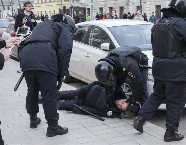 Police help a wounded comrade during fighting with protesters in Pushkin Square, downtown Moscow, Russia, Sunday, March 26, 2017. Thousands of people crowded into Moscow's Pushkin Square on Sunday for an unsanctioned protest against the Russian government, the biggest gathering in a wave of nationwide protests that were the most extensive show of defiance in years. (Photo by Artem Lunev/AP Photo)