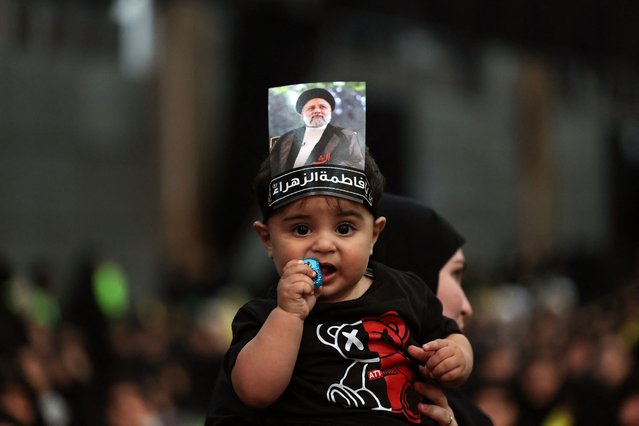 A child carried by a woman waers a picture on his head of Iran's late president Ebrahim Raisi during a rally to mourn the death of the Iranian president and his entourage killed in a recent helicopter accident, in Beirut's southern suburbs on May 24, 2024. (Photo by Anwar Amro/AFP Photo)